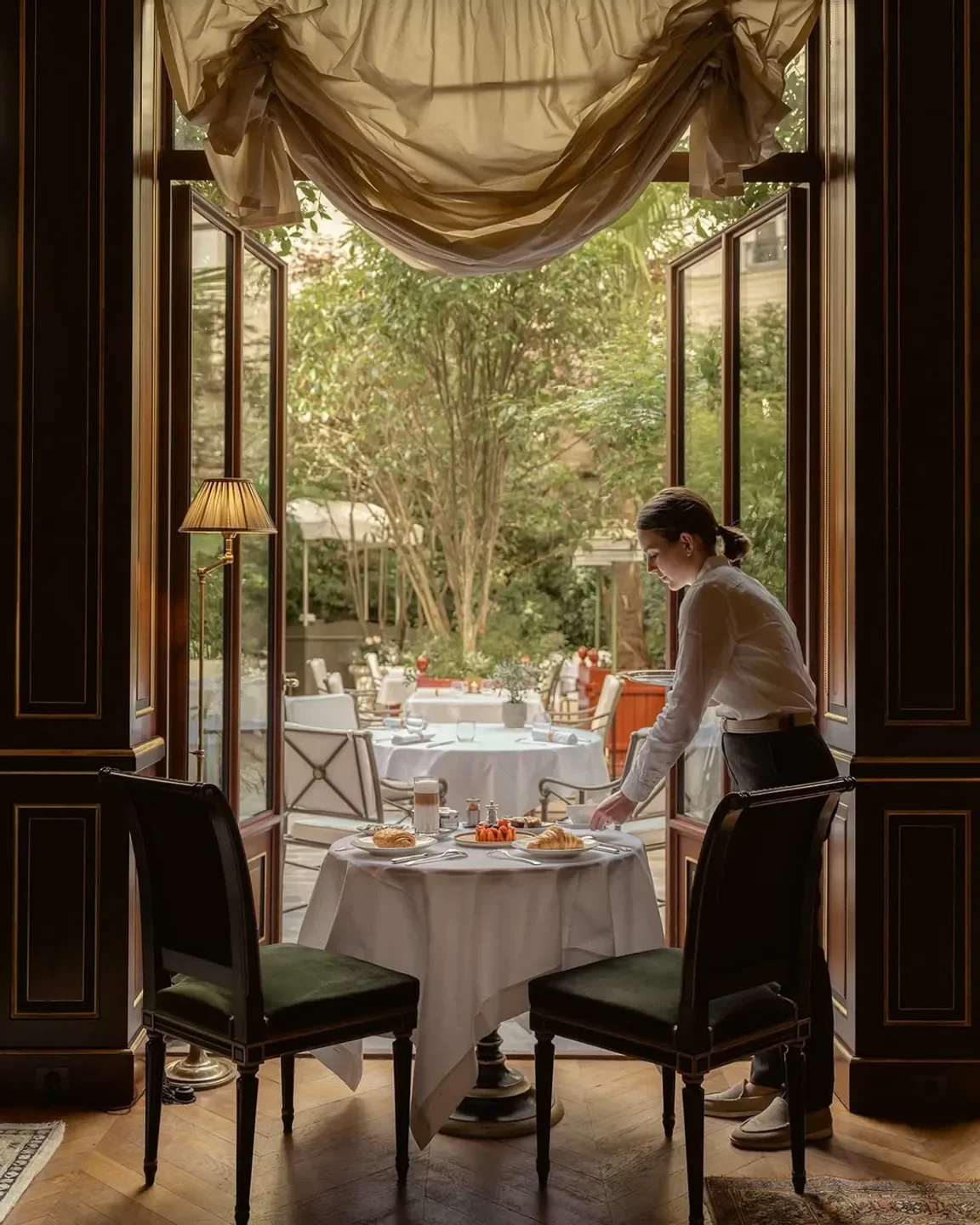 Table setting at Le Gabriel - La Réserve Paris, with a view to the outdoor garden in Paris.