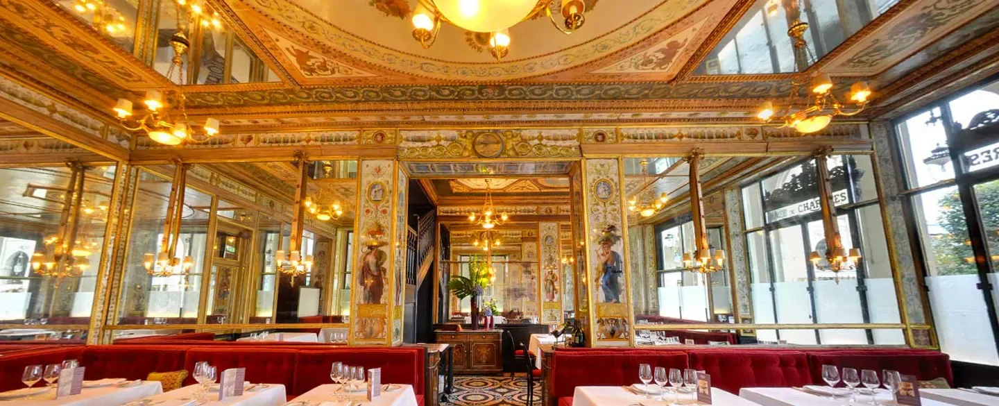 Ornate interior of Le Grand Véfour restaurant in Paris, featuring antique decor and chandeliers.