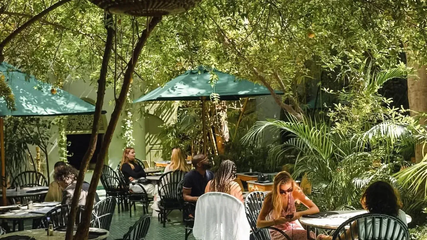 Outdoor dining at Le Jardin restaurant in Marrakech, with lush greenery and umbrellas.