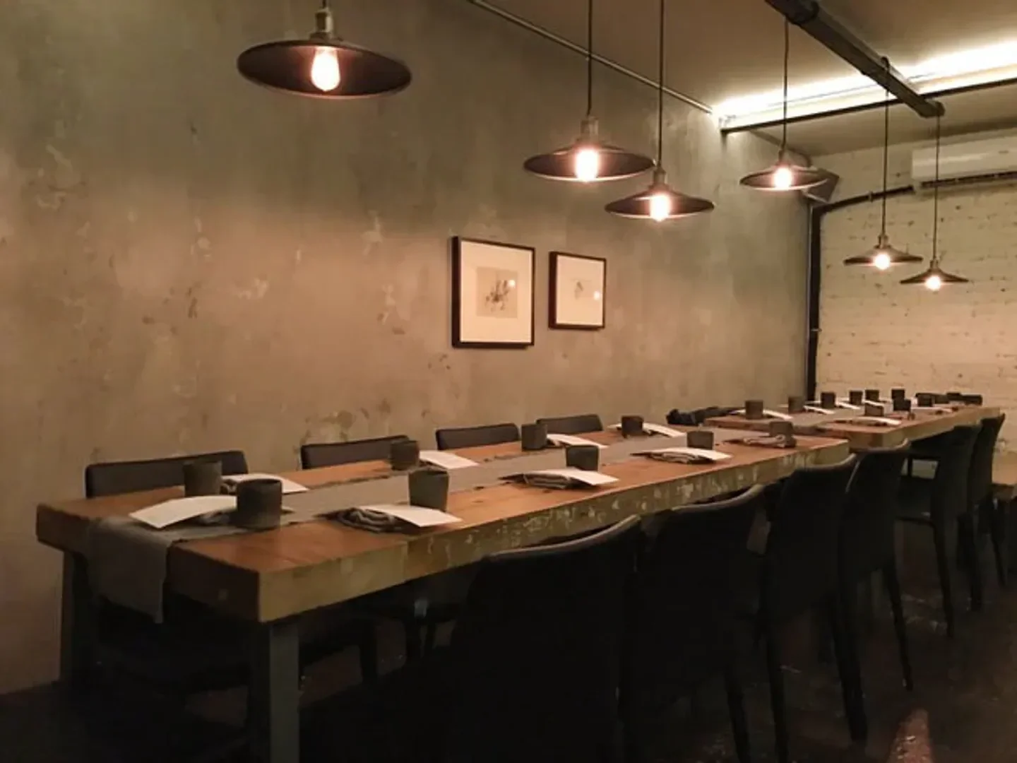 Long wooden table at Le Mousso in Montreal, with hanging lights and minimalist decor