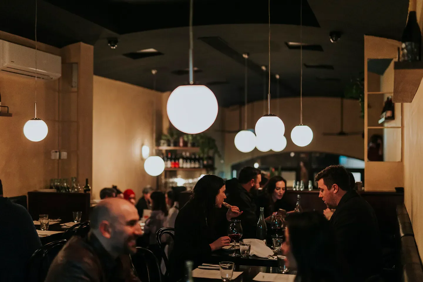 Cozy dining at Le Rebelle in Perth, featuring pendant lights and restaurant patrons.