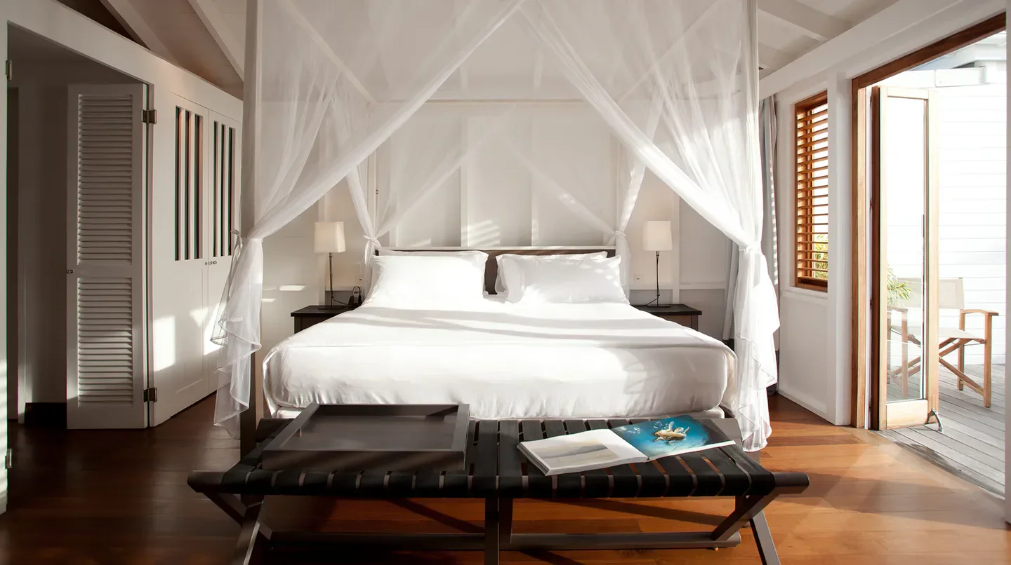 Serene bedroom at Le Sereno in St. Barts, with canopy bed and terrace access.