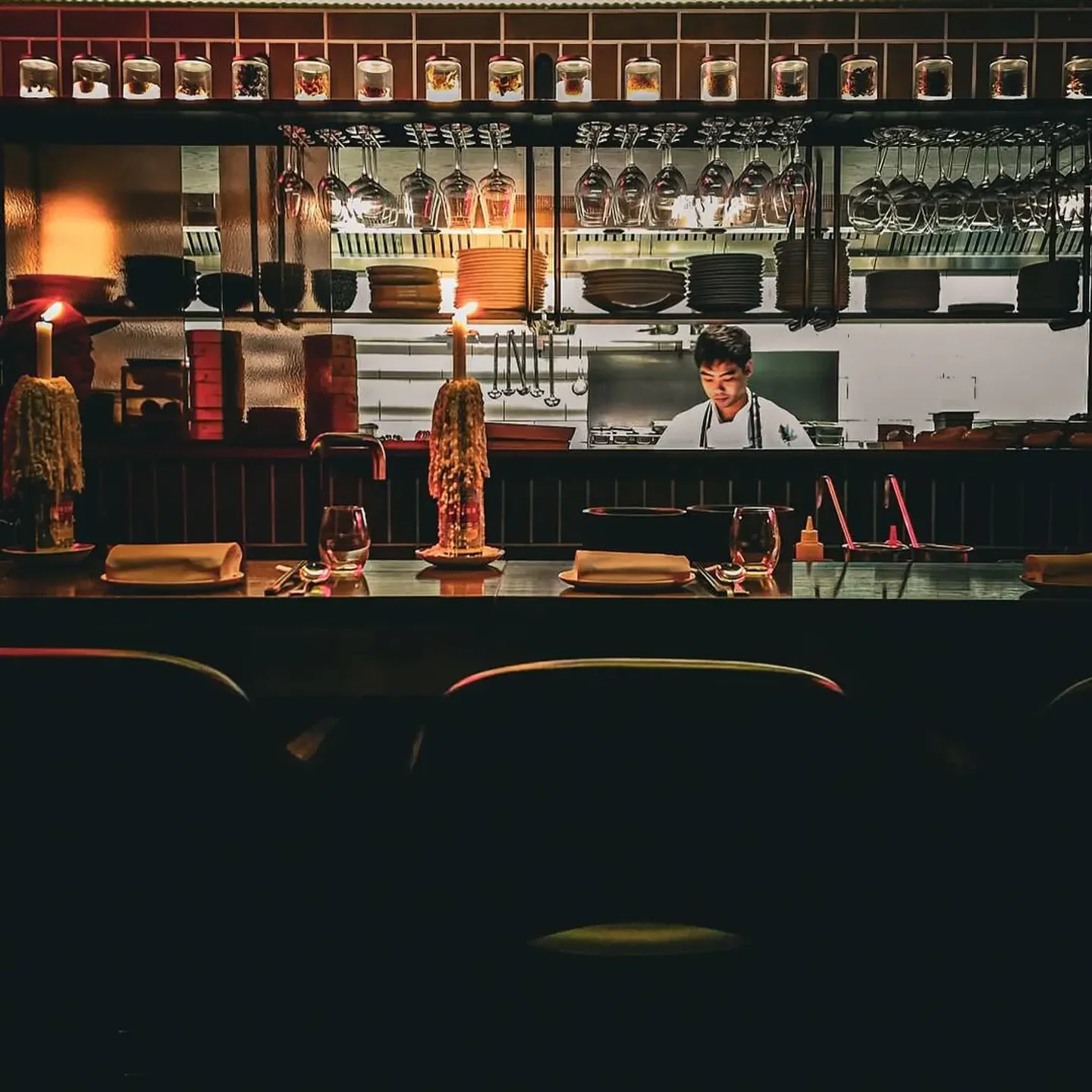 Chef at work inside Lee Ho Fook restaurant in Melbourne with candles and glassware.
