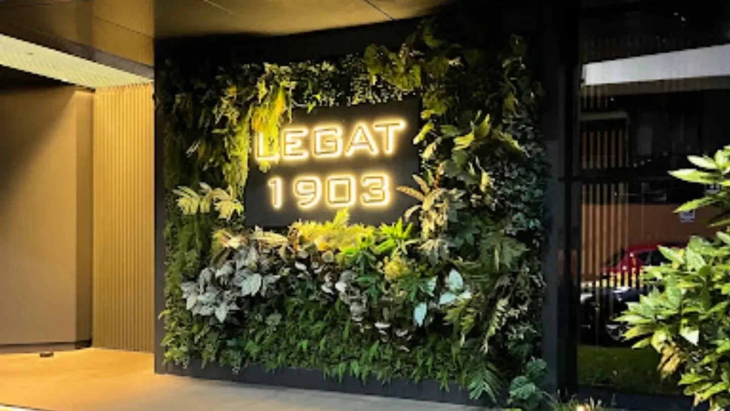 Entrance of Legat 1903 restaurant in Belgrade with a green wall and neon sign