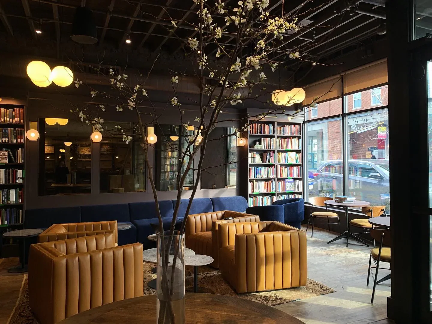Cozy interior of Lehrhaus restaurant in Boston, featuring leather armchairs and a library setting.