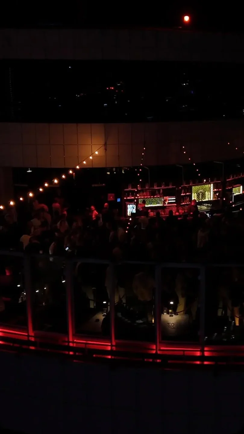Level 27 nightclub in Warsaw buzzing with patrons and illuminated by string lights and red accents.