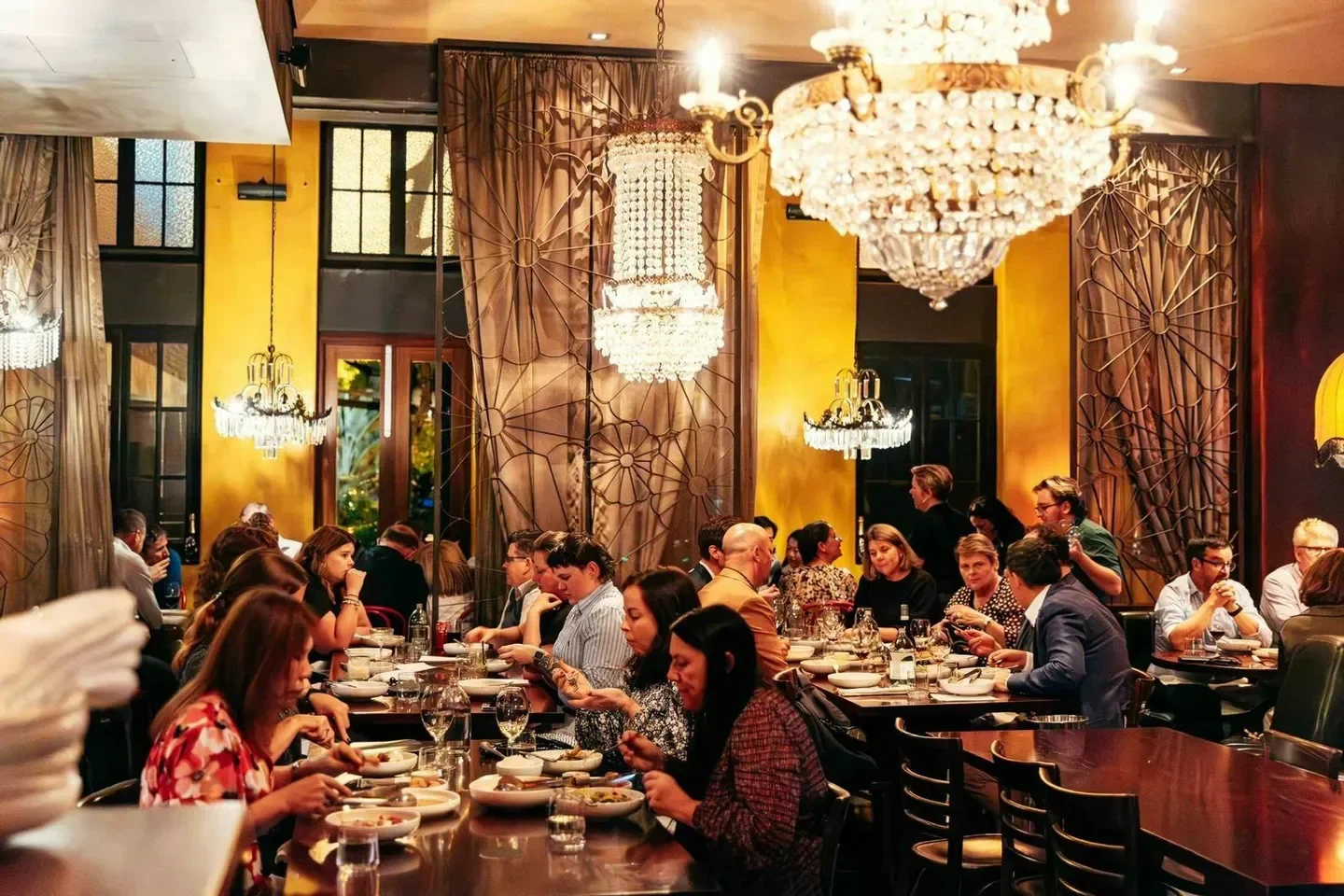 Elegant dining room at Libertine Restaurant & Cocktail Bar in Brisbane, with chandeliers and diners.