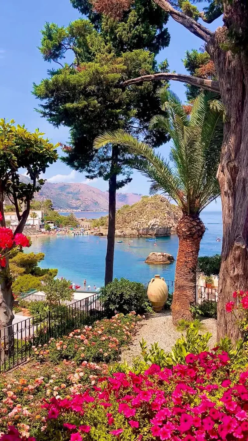 Lush garden overlooking the turquoise waters and beach at Lido Villeggiatura in Sicily, Italy.