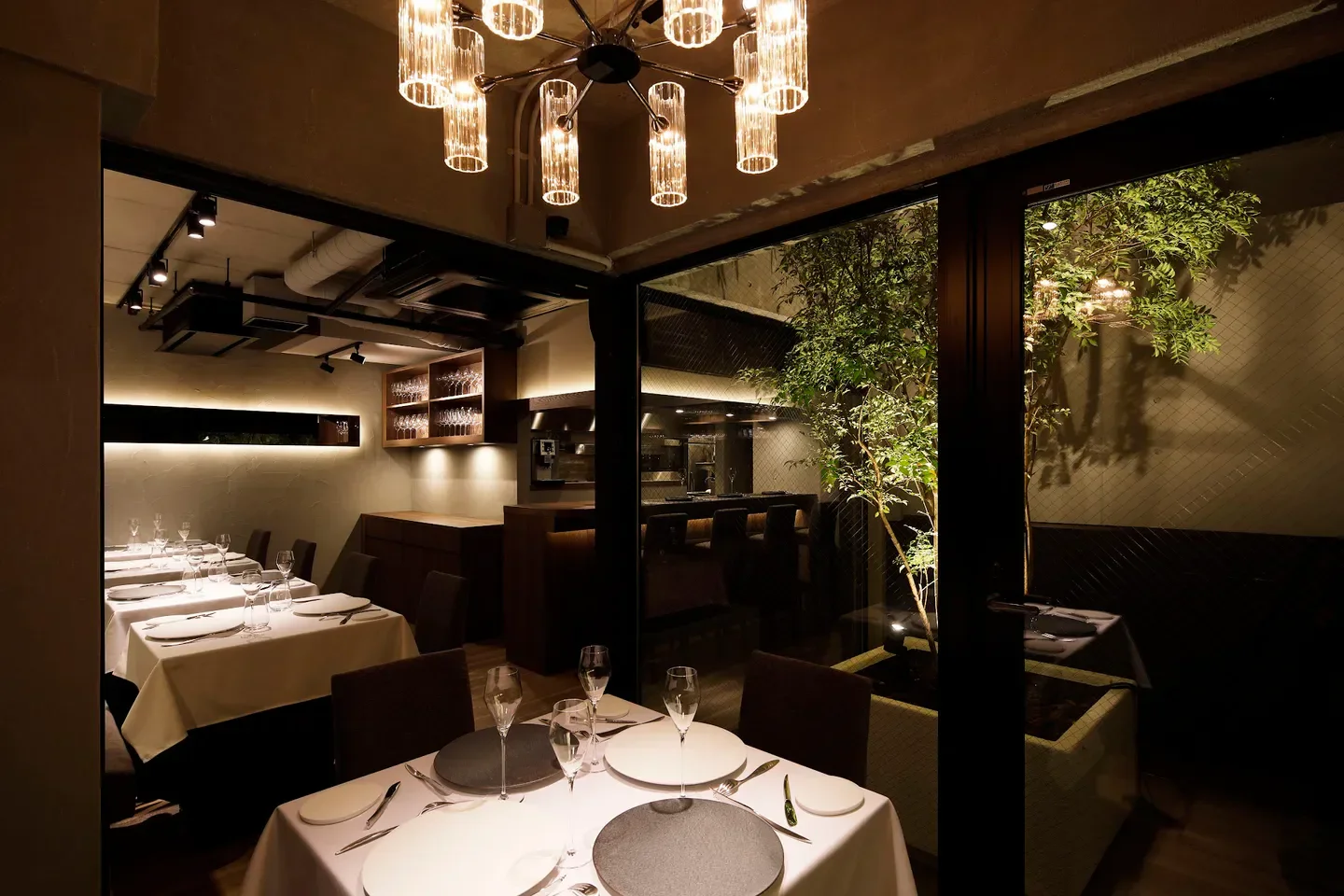 Elegant dining room at L'Intemporel, a Tokyo restaurant, with chandelier and outdoor view.