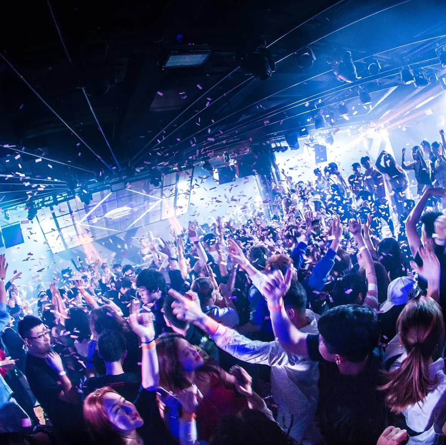 Energetic crowd partying at Linx nightclub in Shanghai with confetti and lights.