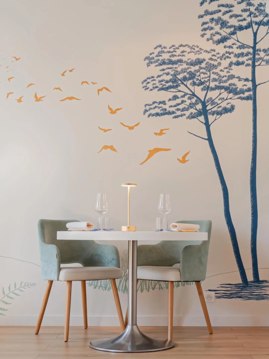 Elegant dining at L'Oiseau Bleu restaurant in Bordeaux, featuring a stylish interior with artistic wall decor and cozy seating.