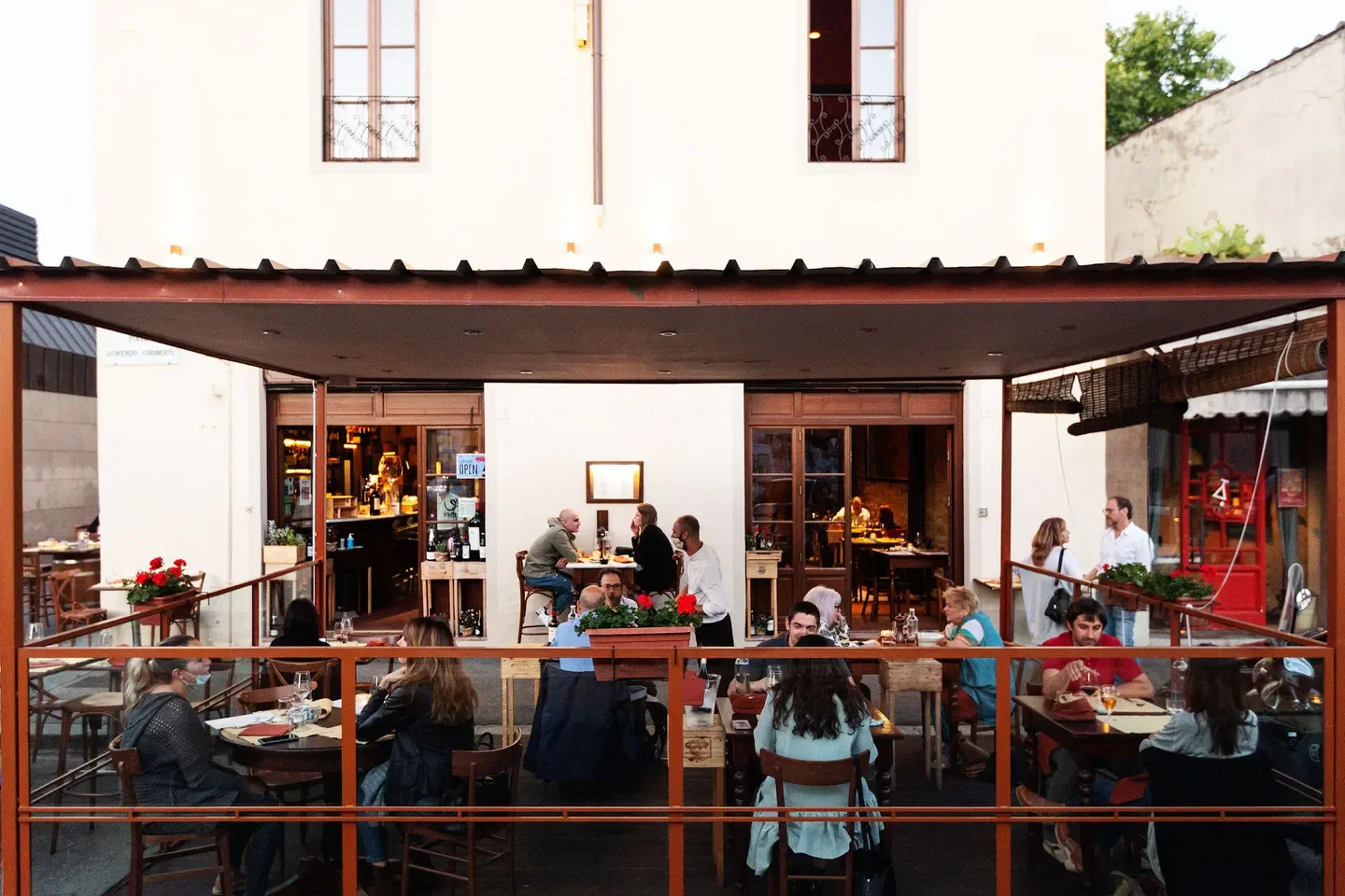 Outdoor dining at L’Ortone restaurant in Florence, with patrons enjoying food and drinks.