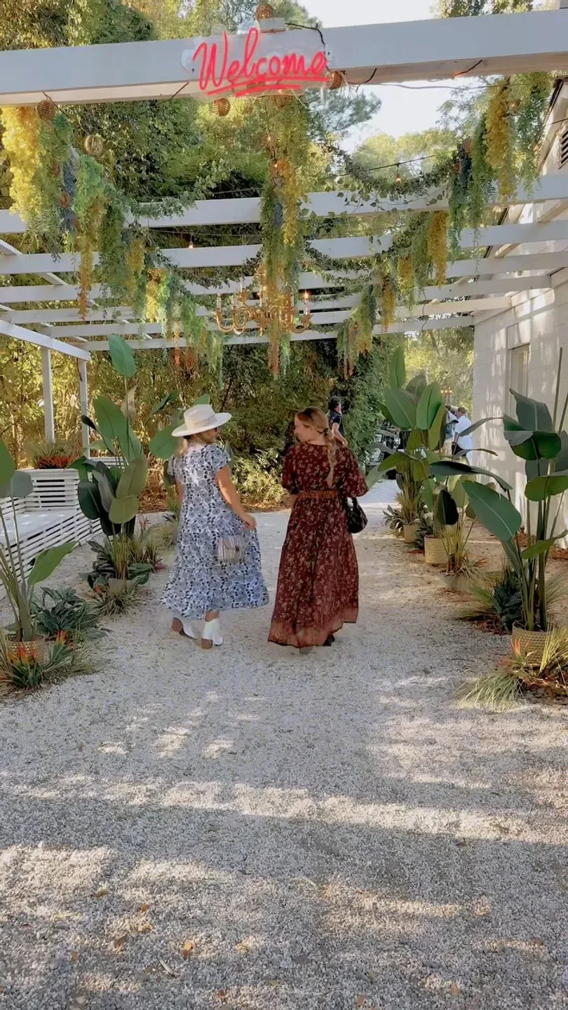 Visitors walking toward the entrance of Lost Isle restaurant in Charleston, with greenery overhead.