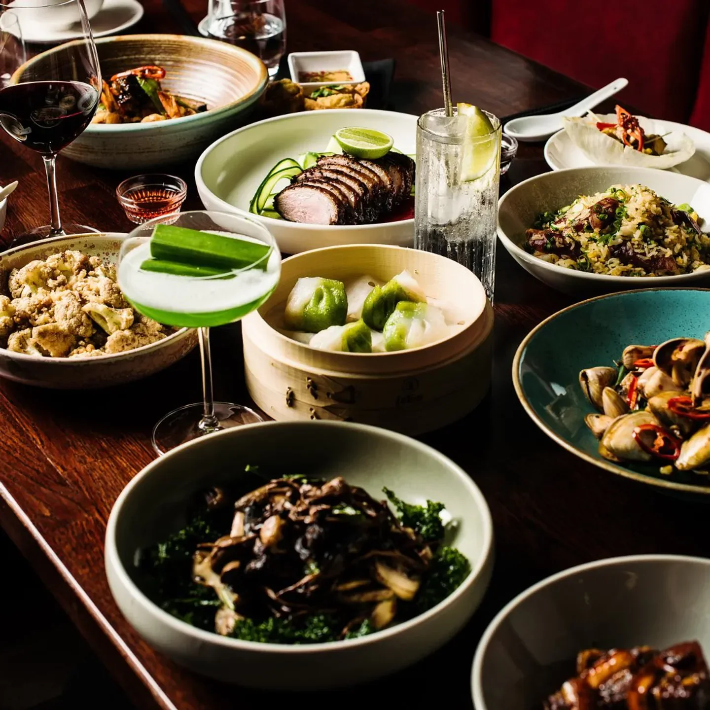 Delicious dishes at Lotus Double Bay in Sydney, including dumplings and cocktails, on a dark wooden table
