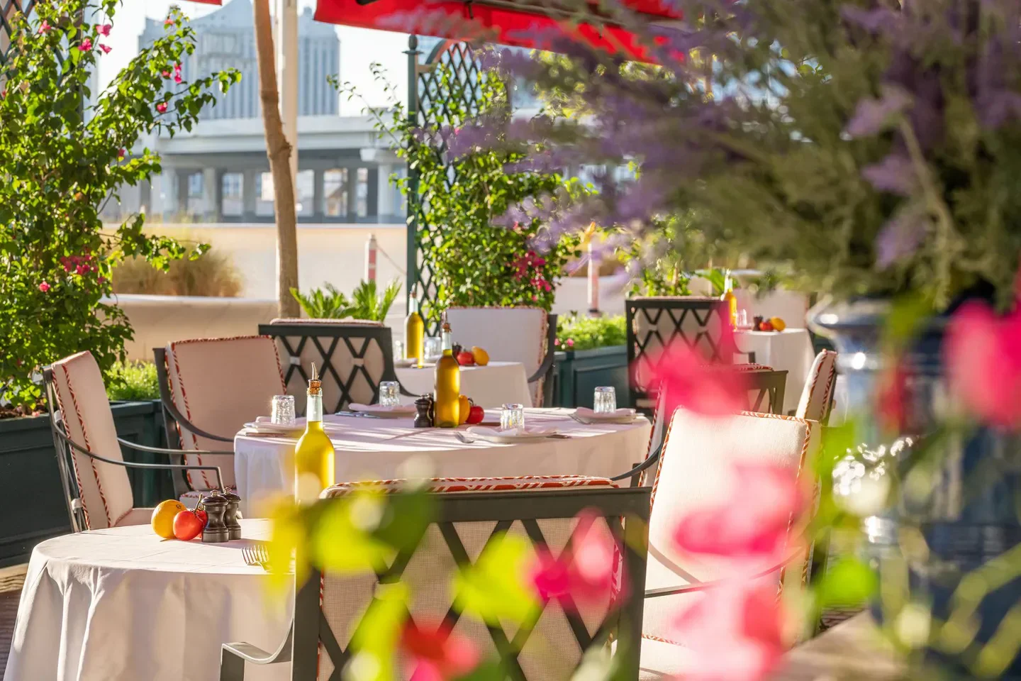 Elegant outdoor dining area at LPM Abu Dhabi restaurant, with flowers and city view.