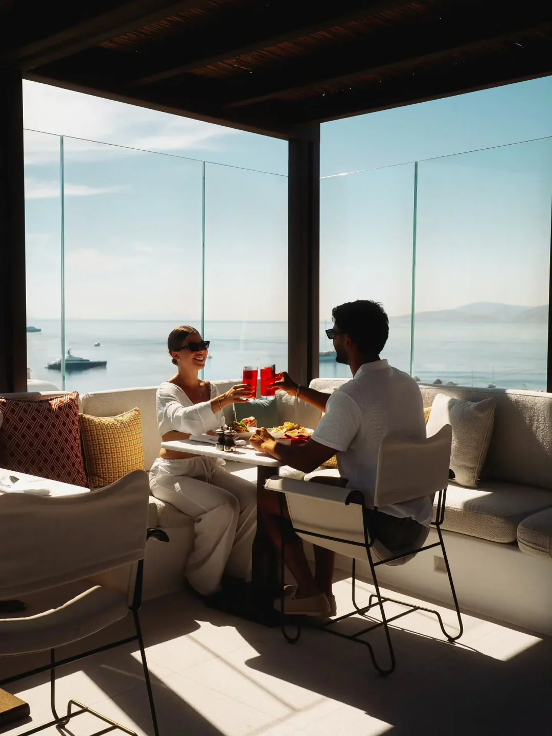 Couple enjoying a meal and drinks at LPM restaurant in Mykonos with a stunning sea view.
