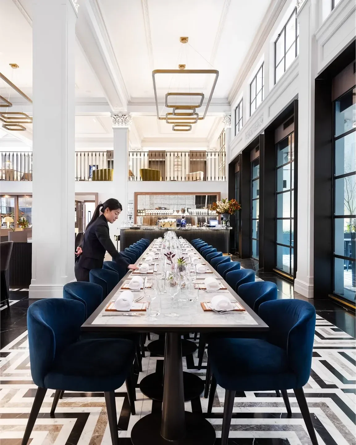 Elegant dining room at Luci restaurant in Melbourne, with prepared table and blue velvet chairs.