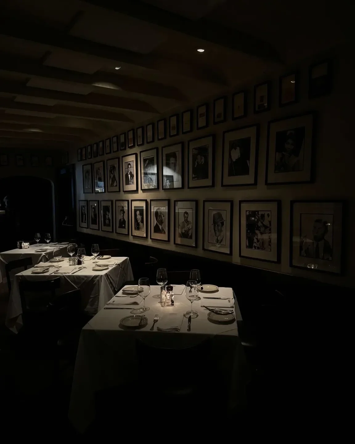 Elegant dining room at Lucky's Steakhouse in Santa Barbara, framed portraits and tables set.