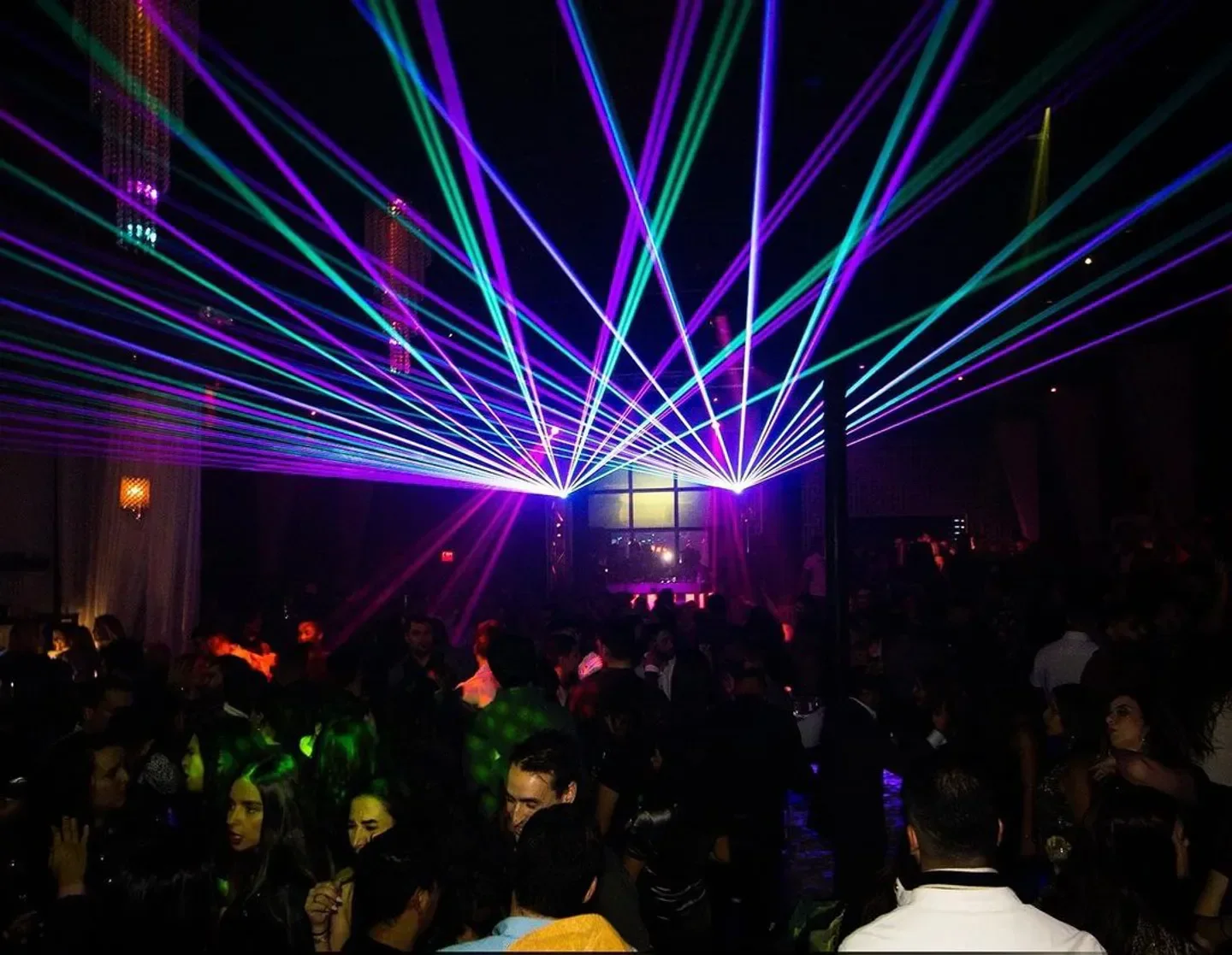 Lumen nightclub in Houston with colorful laser lights over a crowded dance floor.