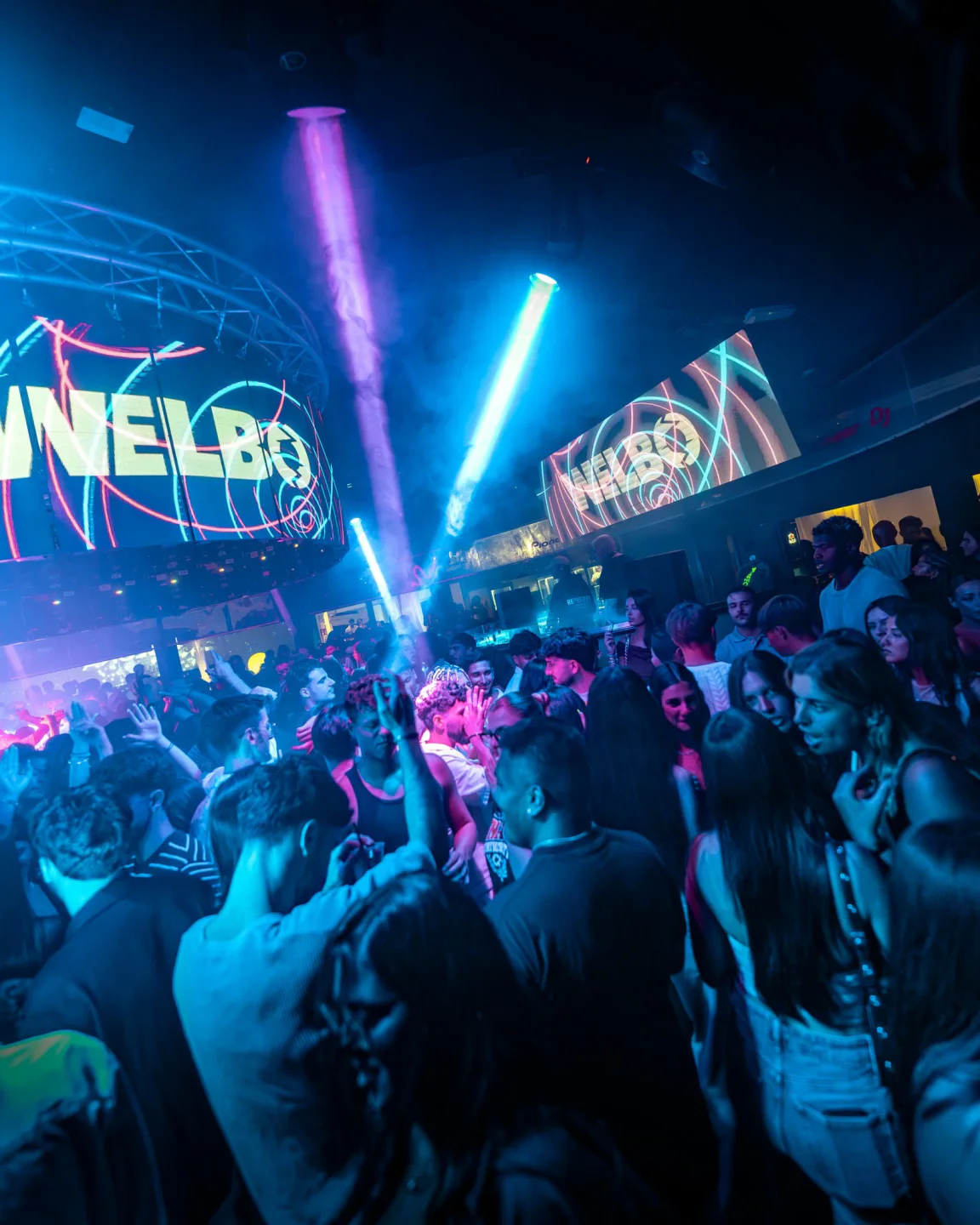 Crowd dancing under blue and purple lights at Luna Glam Club in Sardinia.