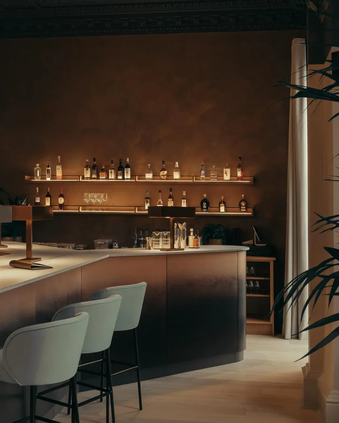 LYLA Edinburgh's stylish bar, featuring backlit shelves, elegant stools, and an inviting atmosphere.