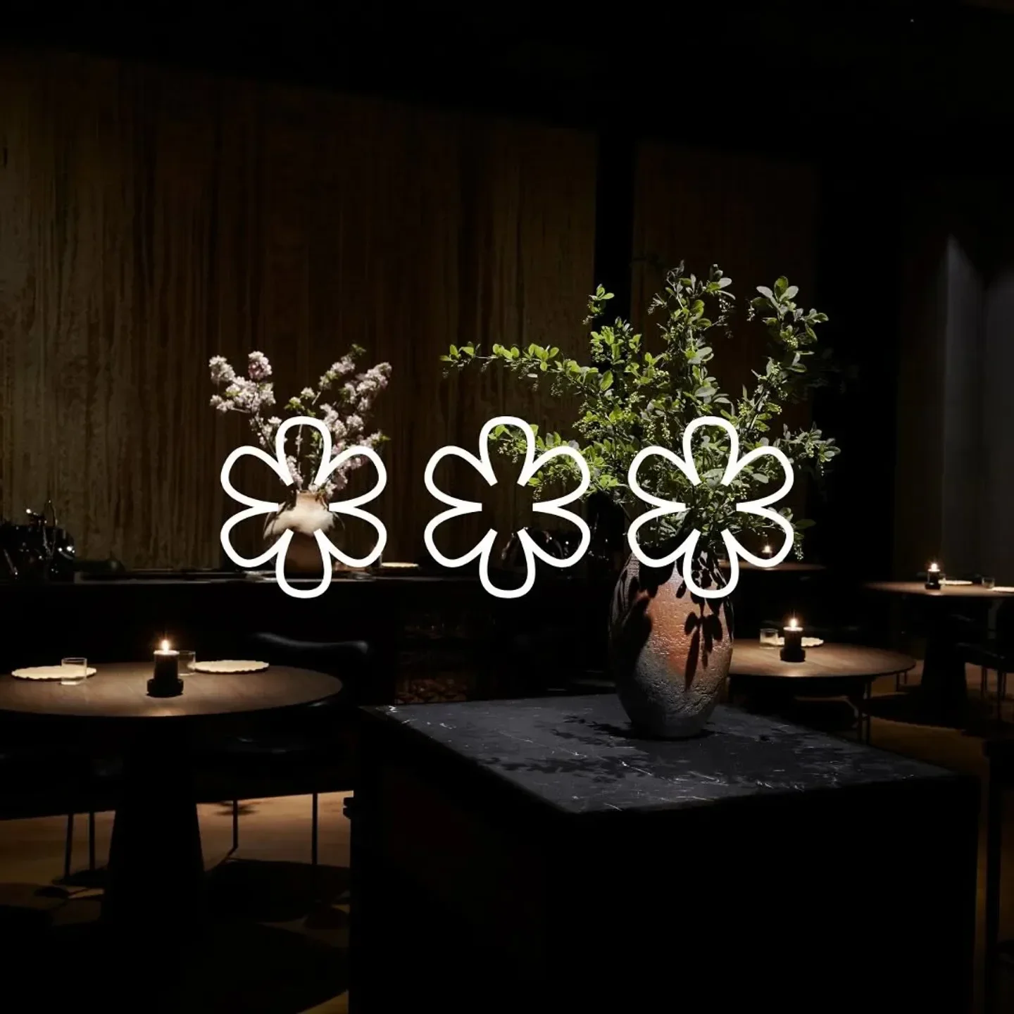 Interior of Maaemo restaurant in Oslo, featuring flowers and dimly lit tables.