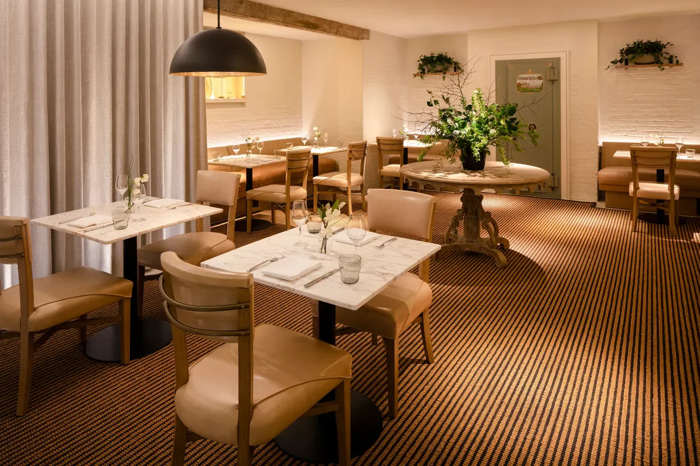 Cozy dining room interior at Magdalena in Baltimore, featuring marble tables and elegant decor.