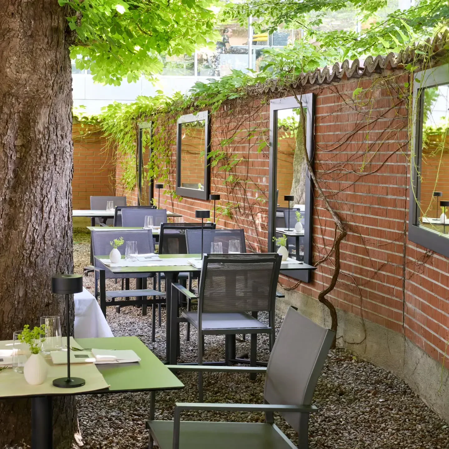 Outdoor dining area at Maihöfli – Oscar de Matos restaurant in Lucerne, surrounded by greenery.
