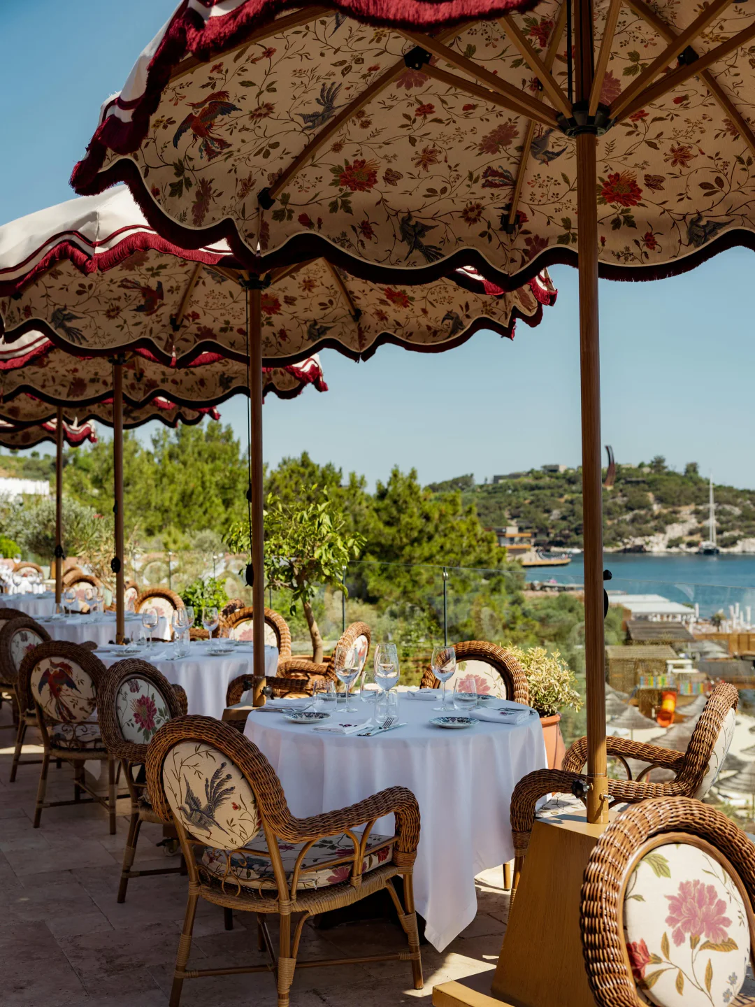 Maison Revka restaurant's outdoor seating with floral umbrellas and scenic coastal view.