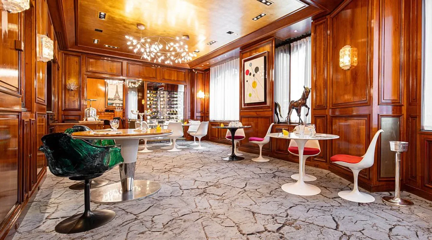 Elegant interior of Maison Rostang restaurant in Paris, featuring wooden paneling and stylish chairs.