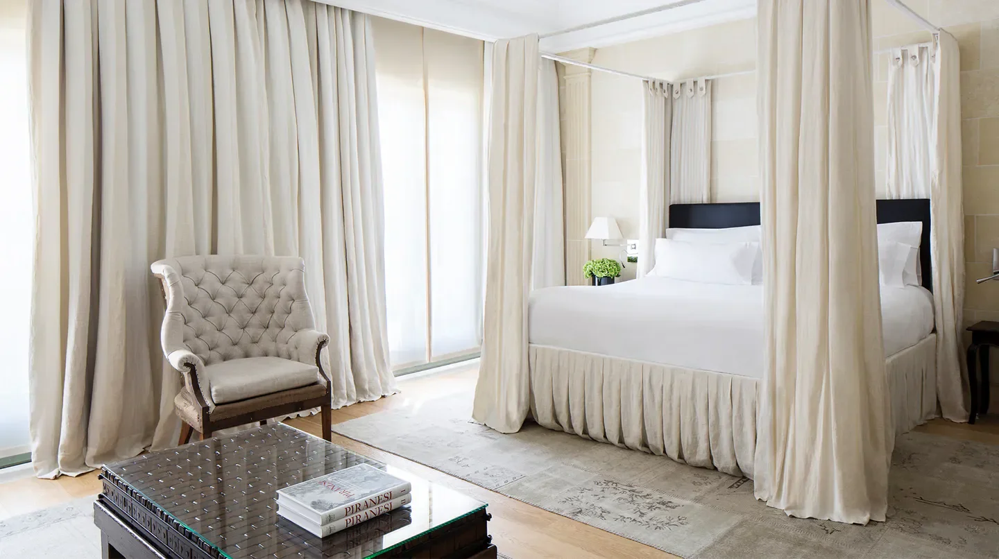 Elegant bedroom interior at the Majestic Hotel & Spa in Barcelona with canopy bed and armchair.