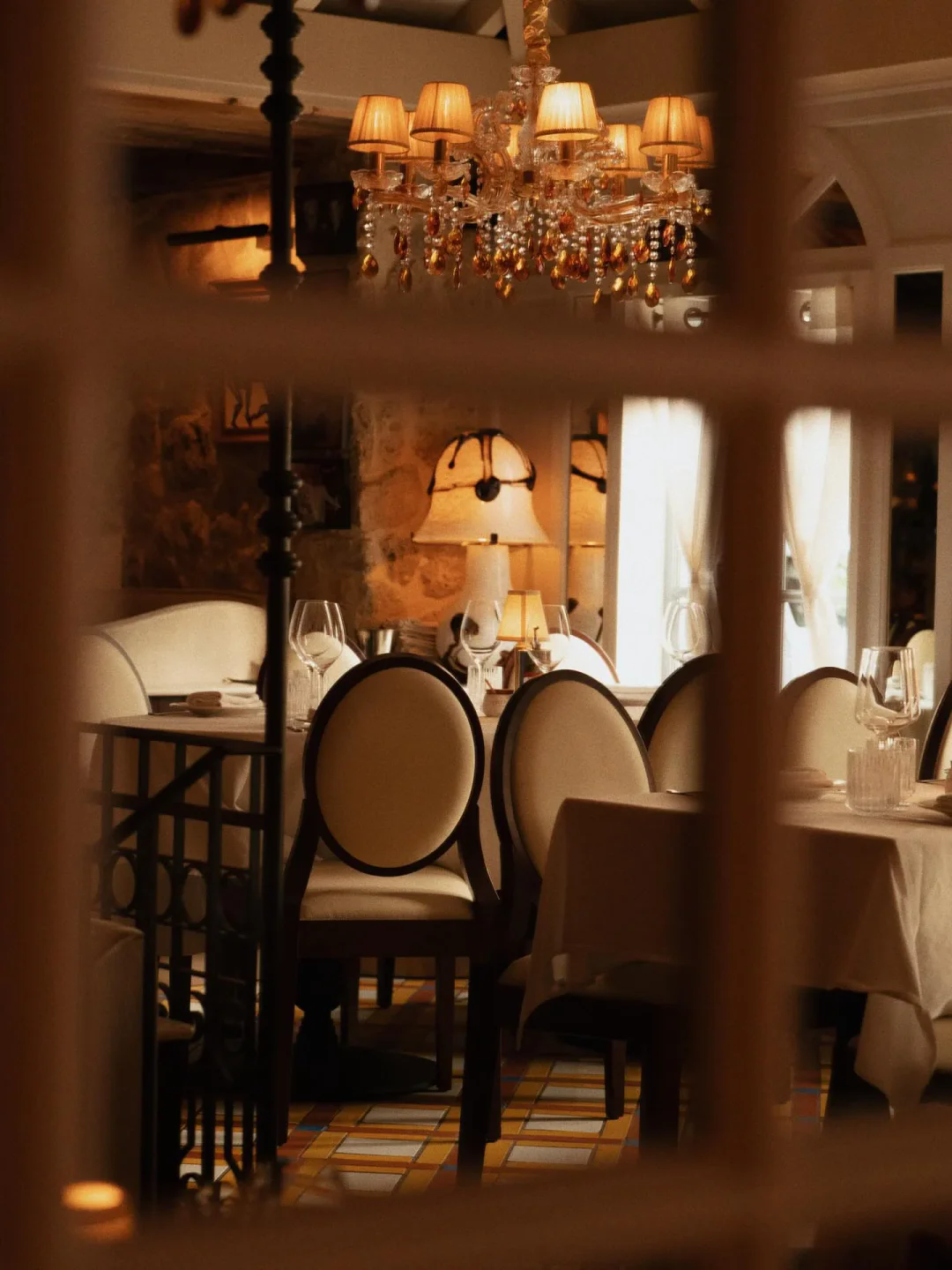 Elegant dining room interior of Mamo restaurant with a crystal chandelier and set tables.
