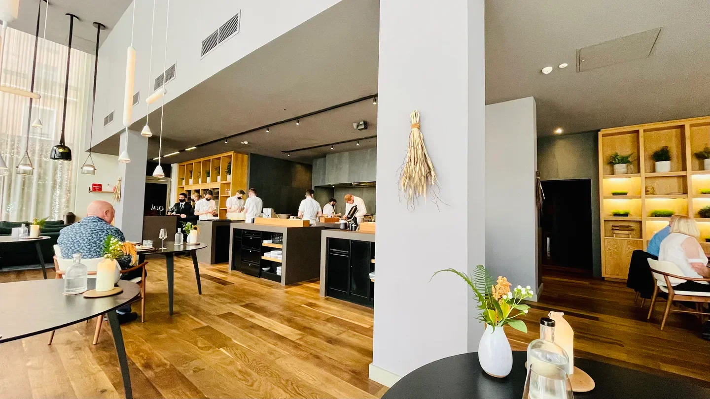 Interior of Mana restaurant in Manchester, with chefs in the kitchen and dining area.