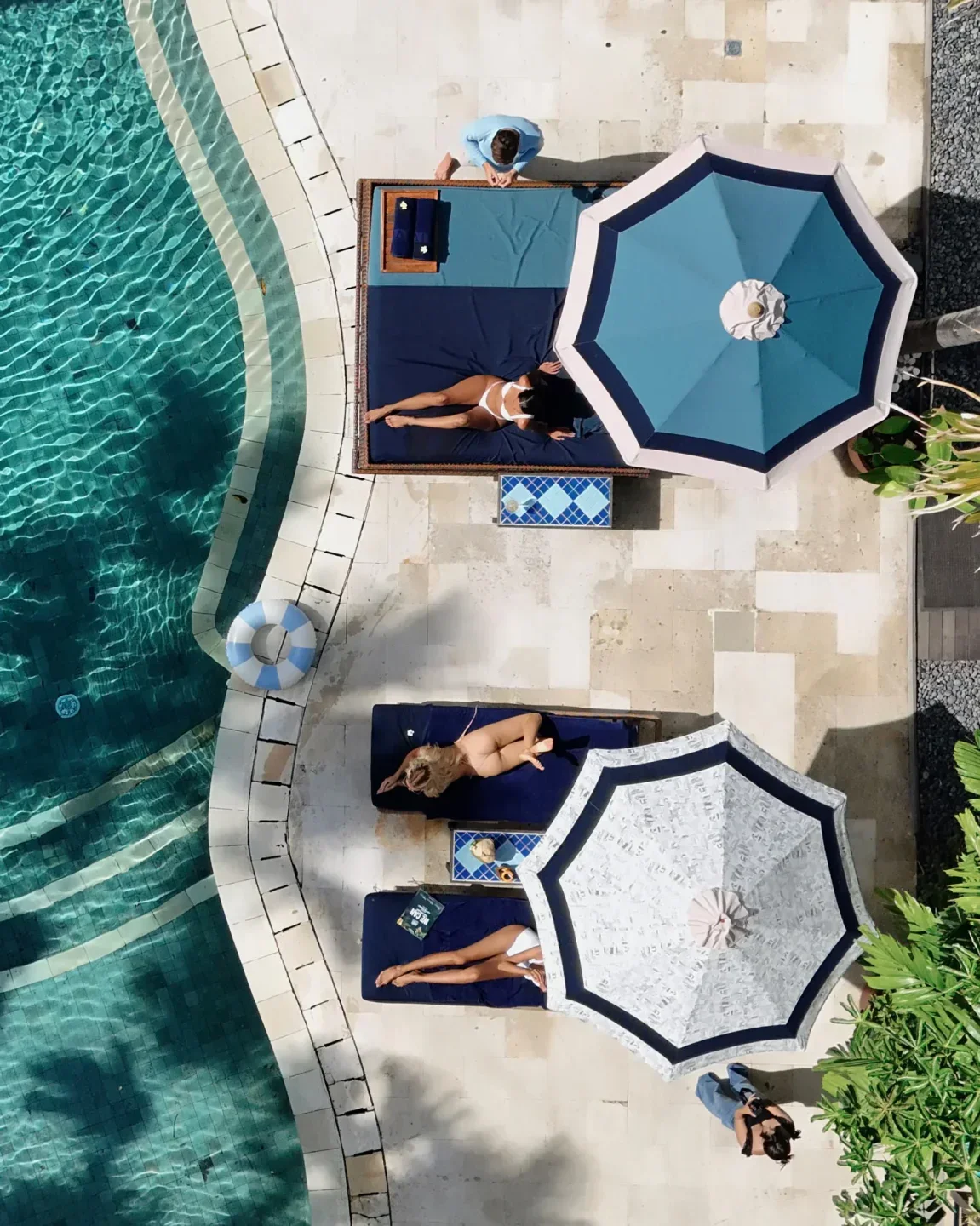Manari Beach House in Bali: Guests relaxing by the pool under umbrellas.