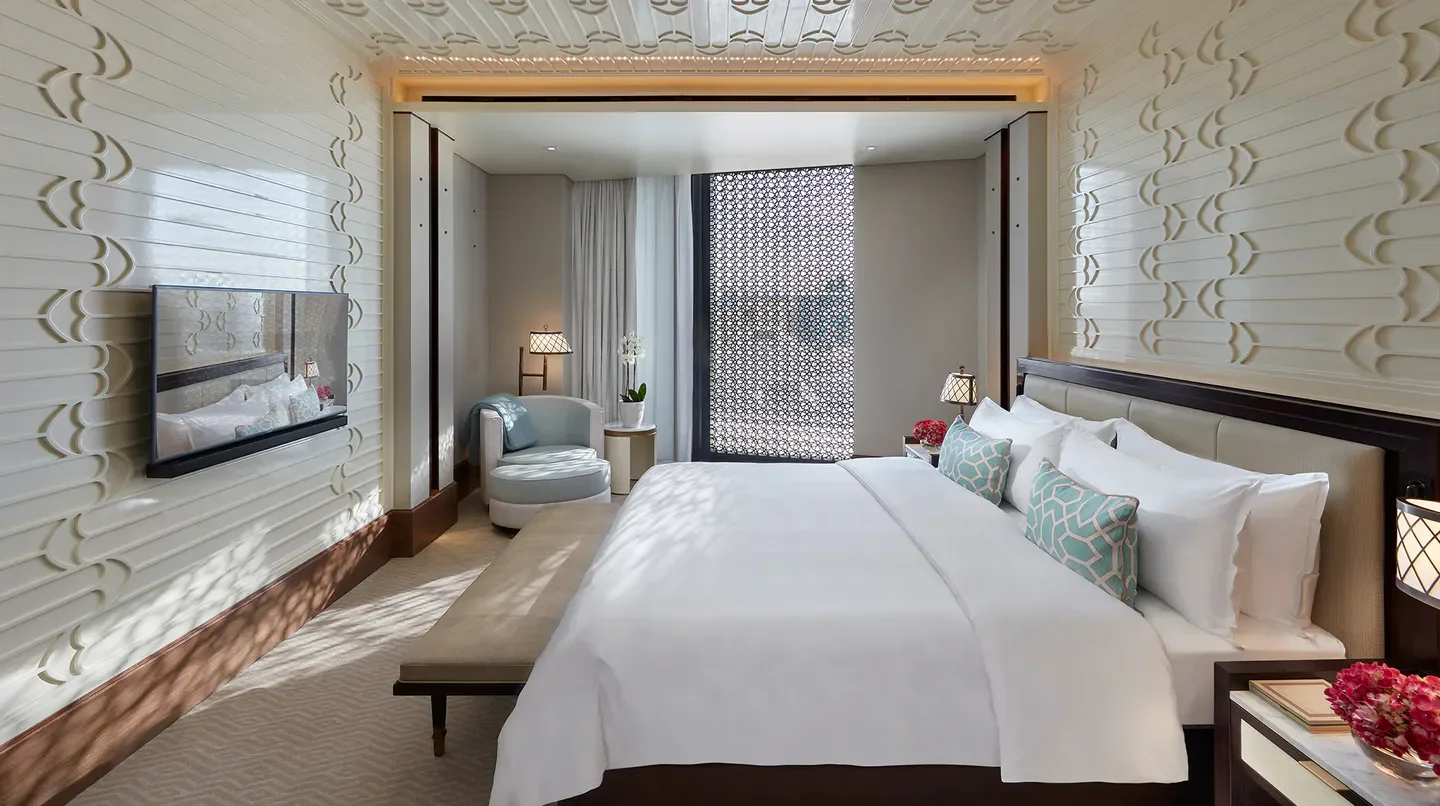 Luxury bedroom at Mandarin Oriental, Doha, with ornate wall detailing and chic decor.