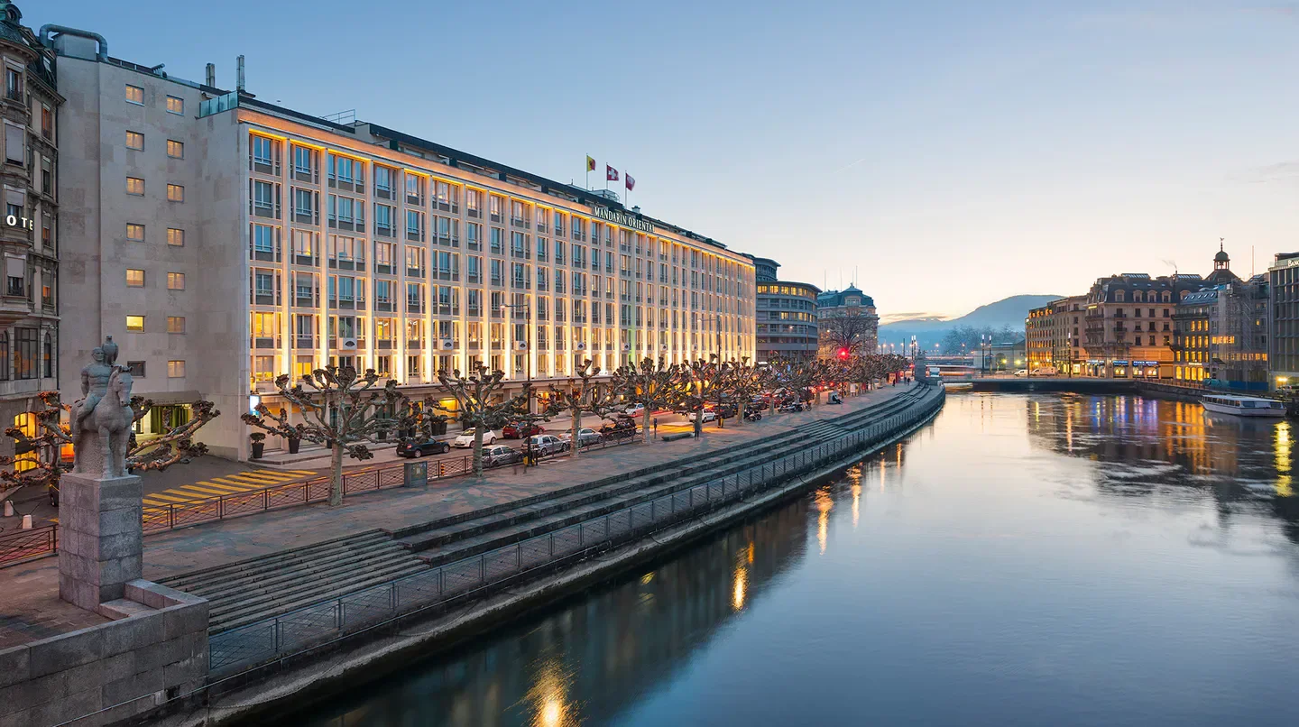Mandarin Oriental, Geneva, waterfront view in Geneva at dusk, illuminated hotel facade.