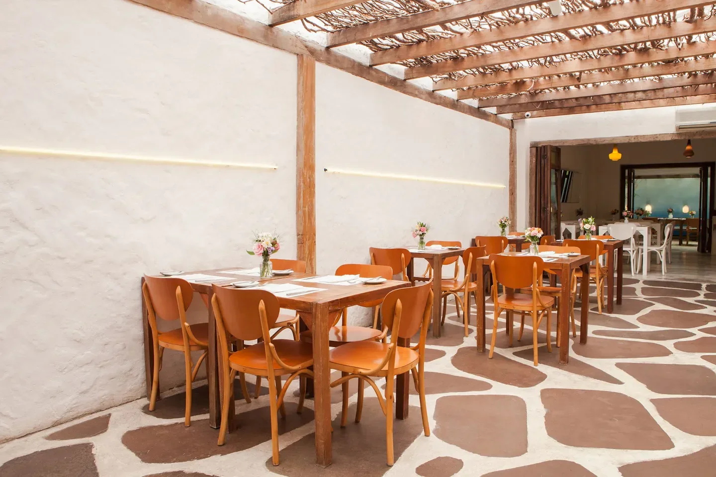 Outdoor dining area at Maní restaurant in Sao Paulo, featuring wood tables and chairs