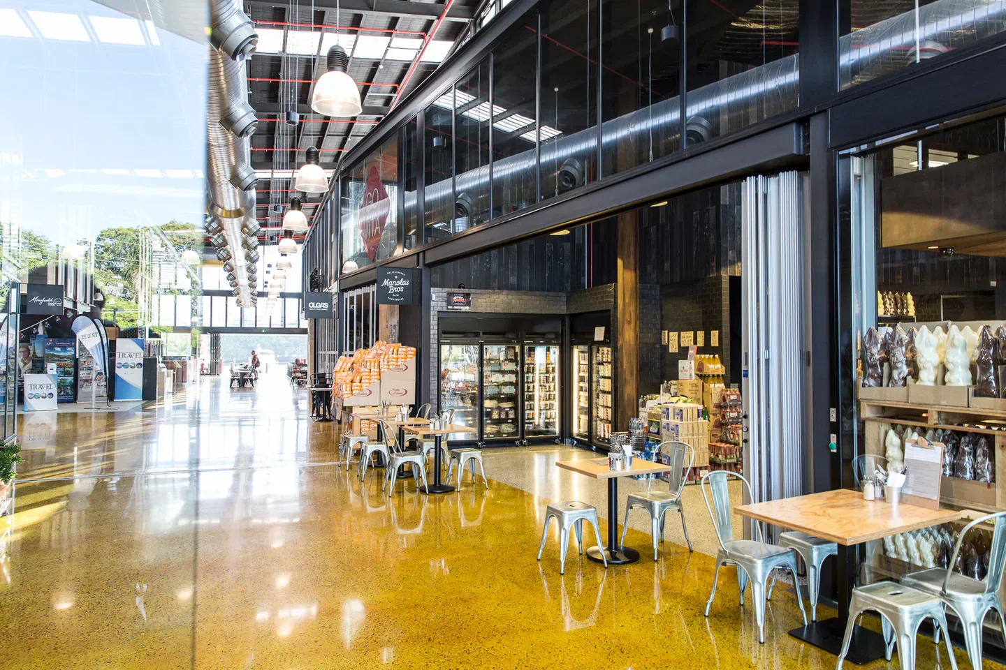 Interior of Manolas Deli Bar Bistro on the Gold Coast with bright, modern decor and tables.
