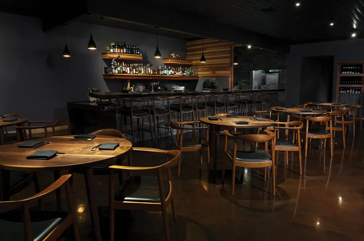 Interior of Matsu restaurant in San Diego featuring round tables and a bar.