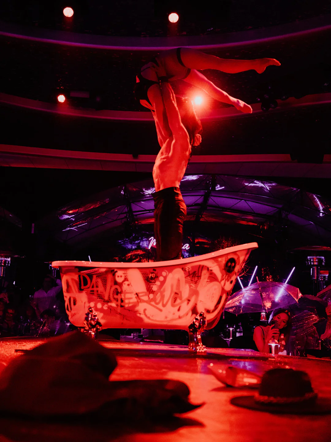 Acrobatic performers in a bathtub at Medusa nightclub in Cannes, illuminated by red lights.