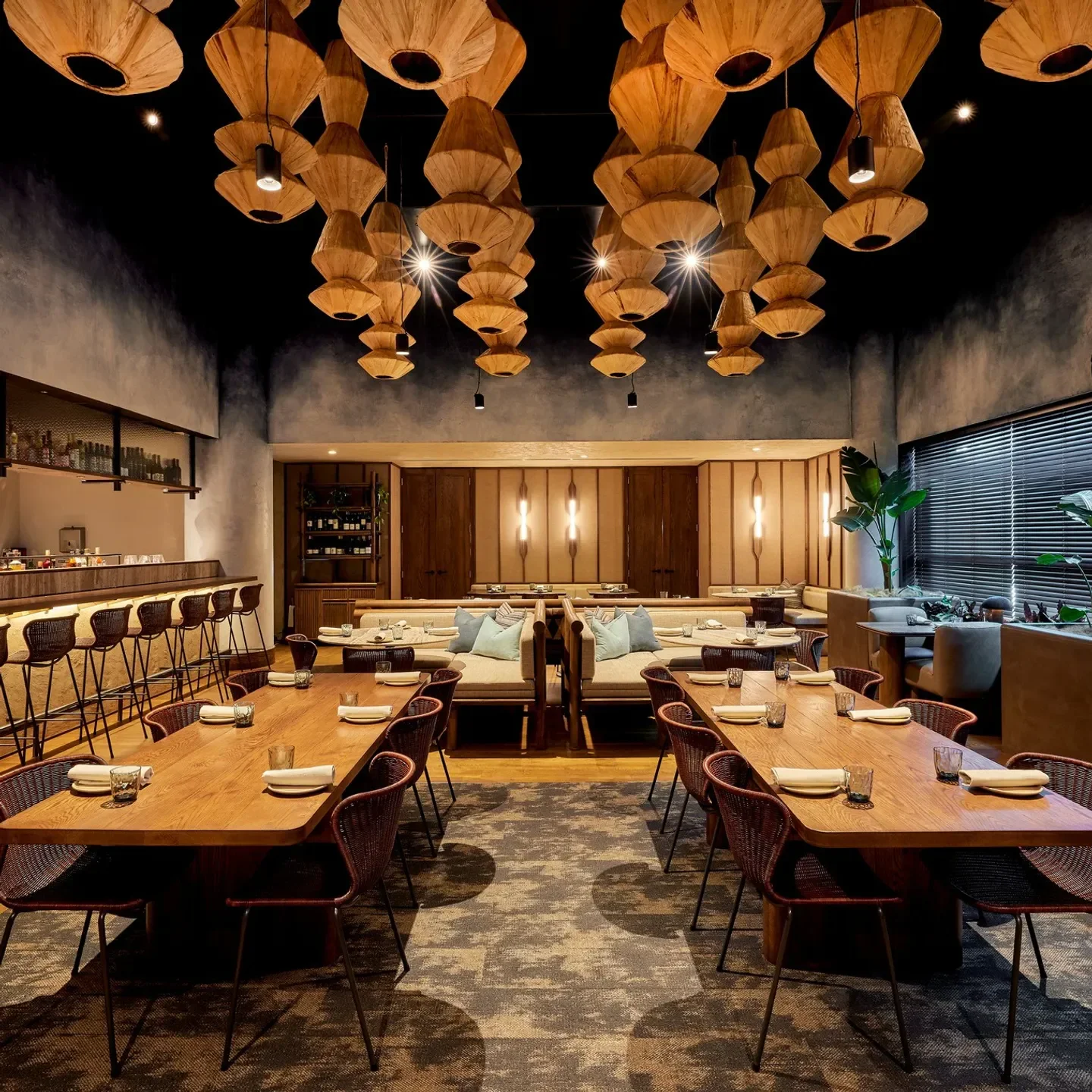 Interior of Metita restaurant in Auckland, with wooden tables and unique ceiling lights.