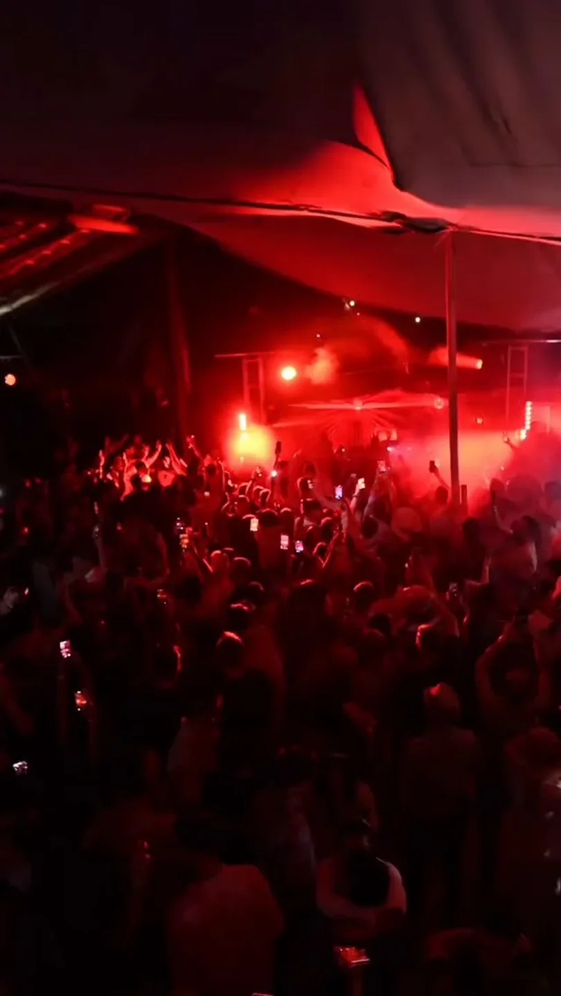 Energetic crowd at Mia nightclub in Tulum, Mexico, enjoying a night out with red stage lighting and music.