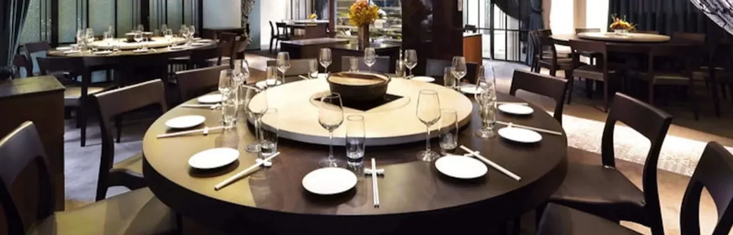 Round tables at Ming Fu Restaurant in Taipei, ready for dinner service with chopsticks and glasses.
