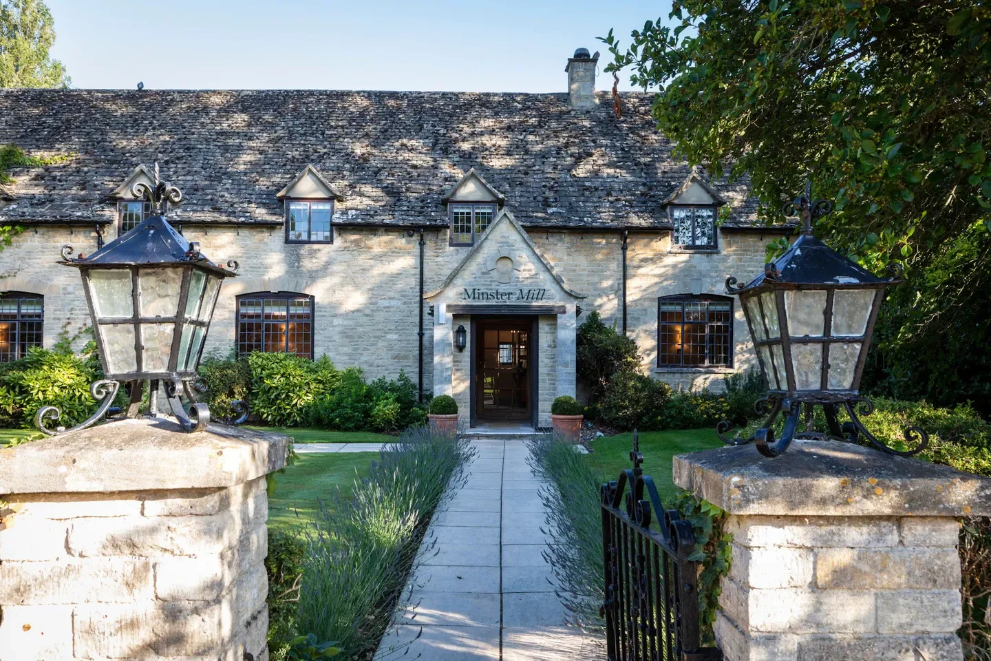 Entrance to Minster Mill restaurant in the Cotswolds with stone facade and lanterns.