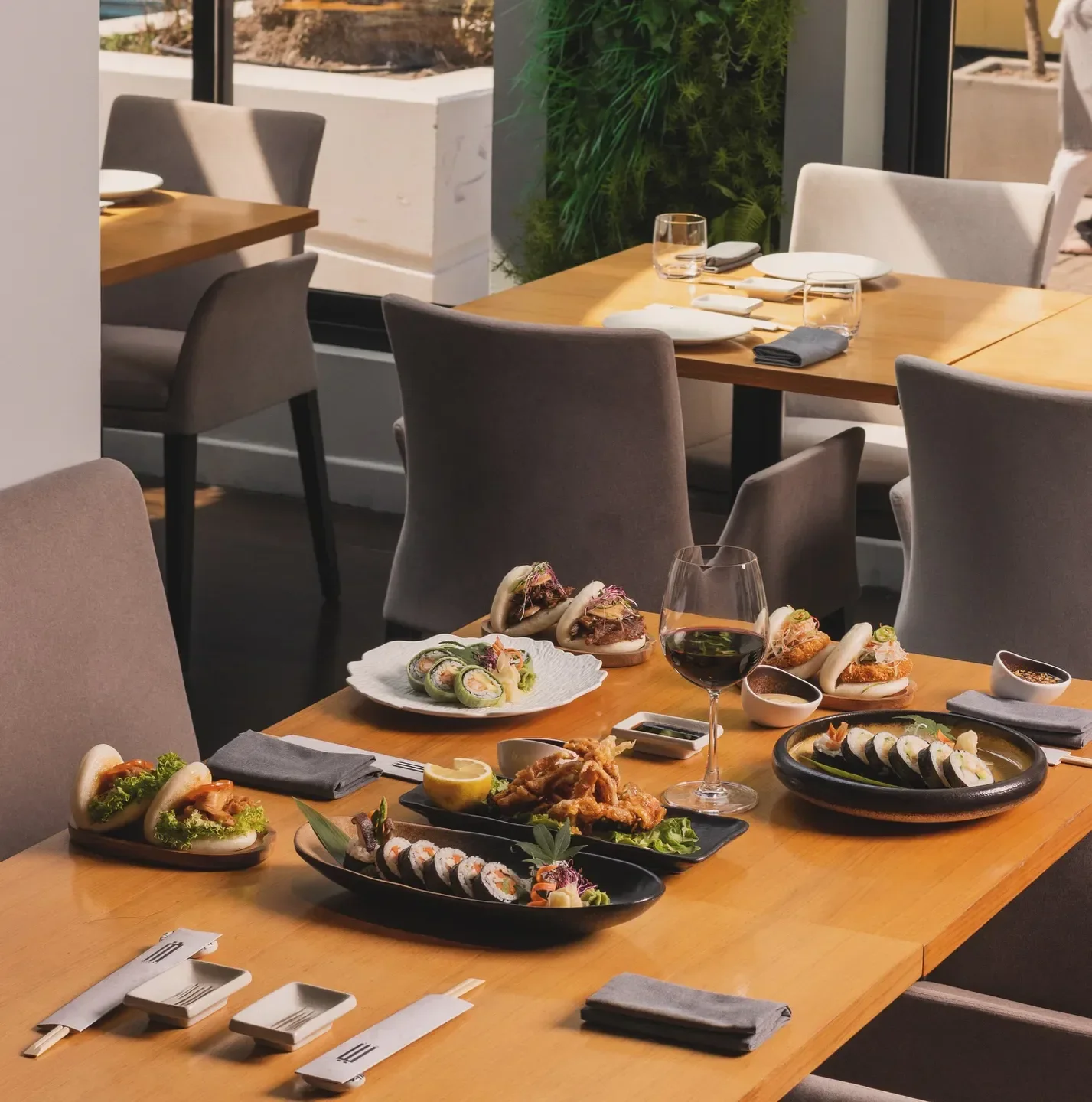 Table setting at Mirai restaurant in Manama, featuring sushi, bao buns and wine.