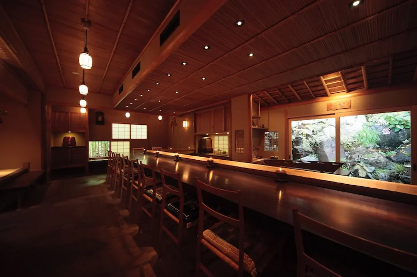 Interior of Mizai restaurant in Kyoto, featuring a long wooden counter and garden view.