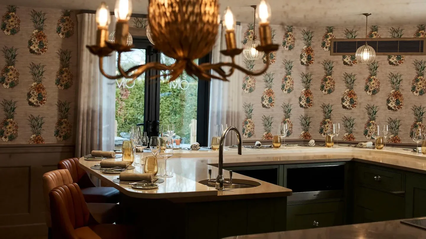 Interior of MO Restaurant in the Cotswolds with elegant pineapple wallpaper and dining table.