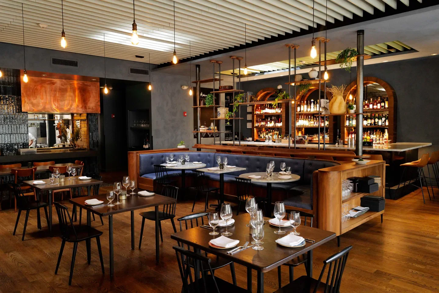 Interior of Moëca restaurant in Boston with stylish tables and bar.