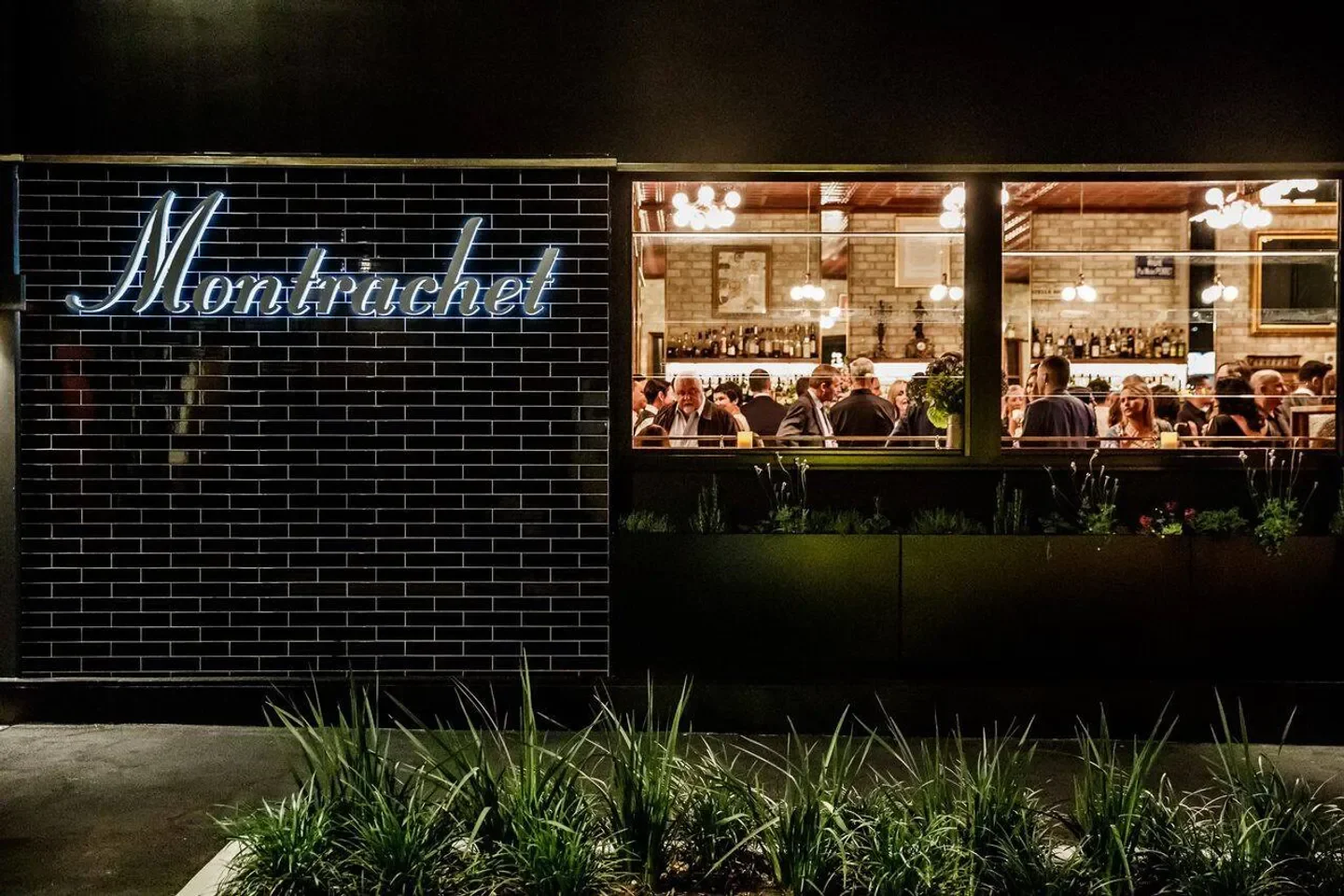 Montrachet restaurant in Brisbane at night, neon sign and diners inside.