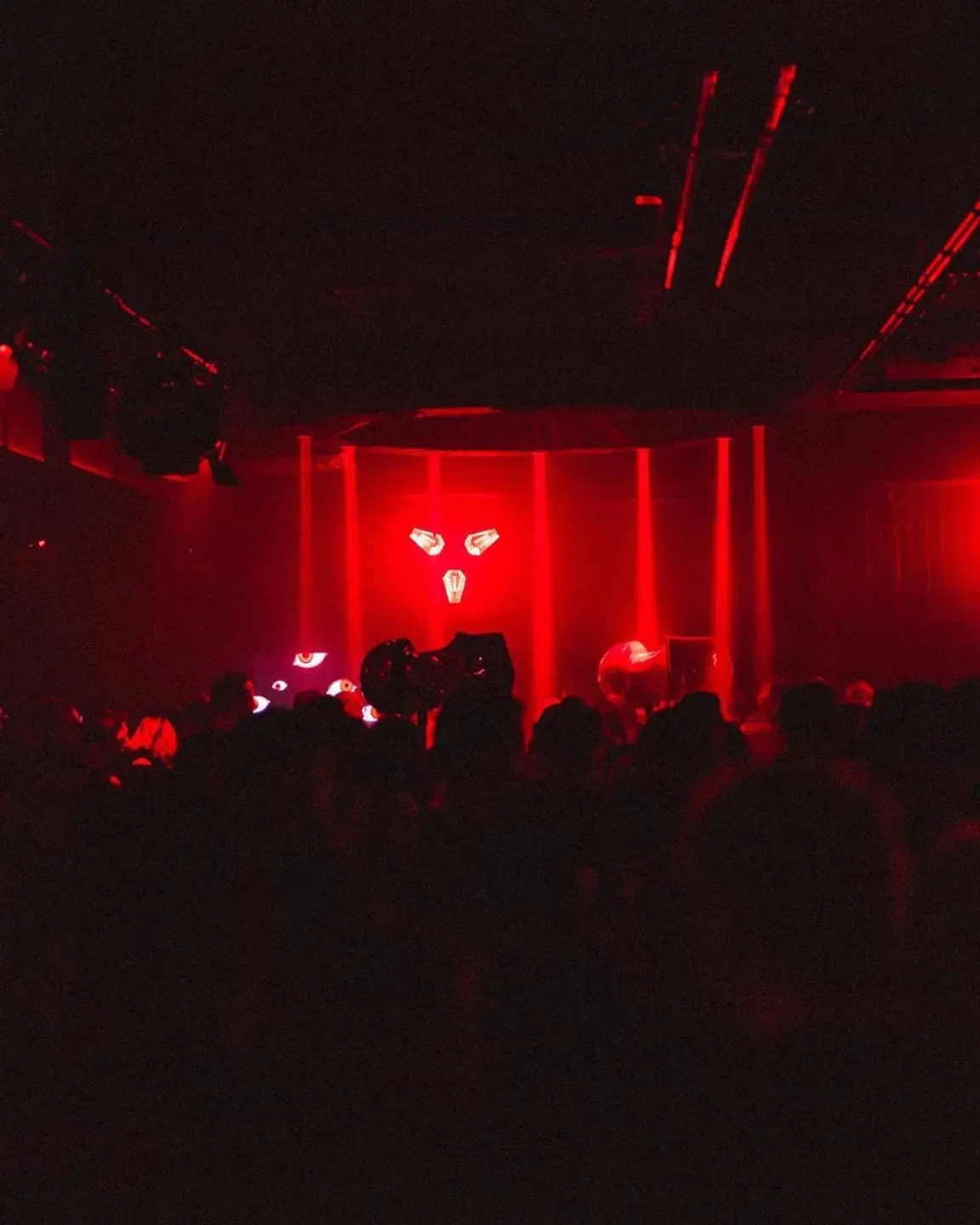 Red-lit interior of Moon nightclub in Warsaw with crowd silhouette and stage lights.